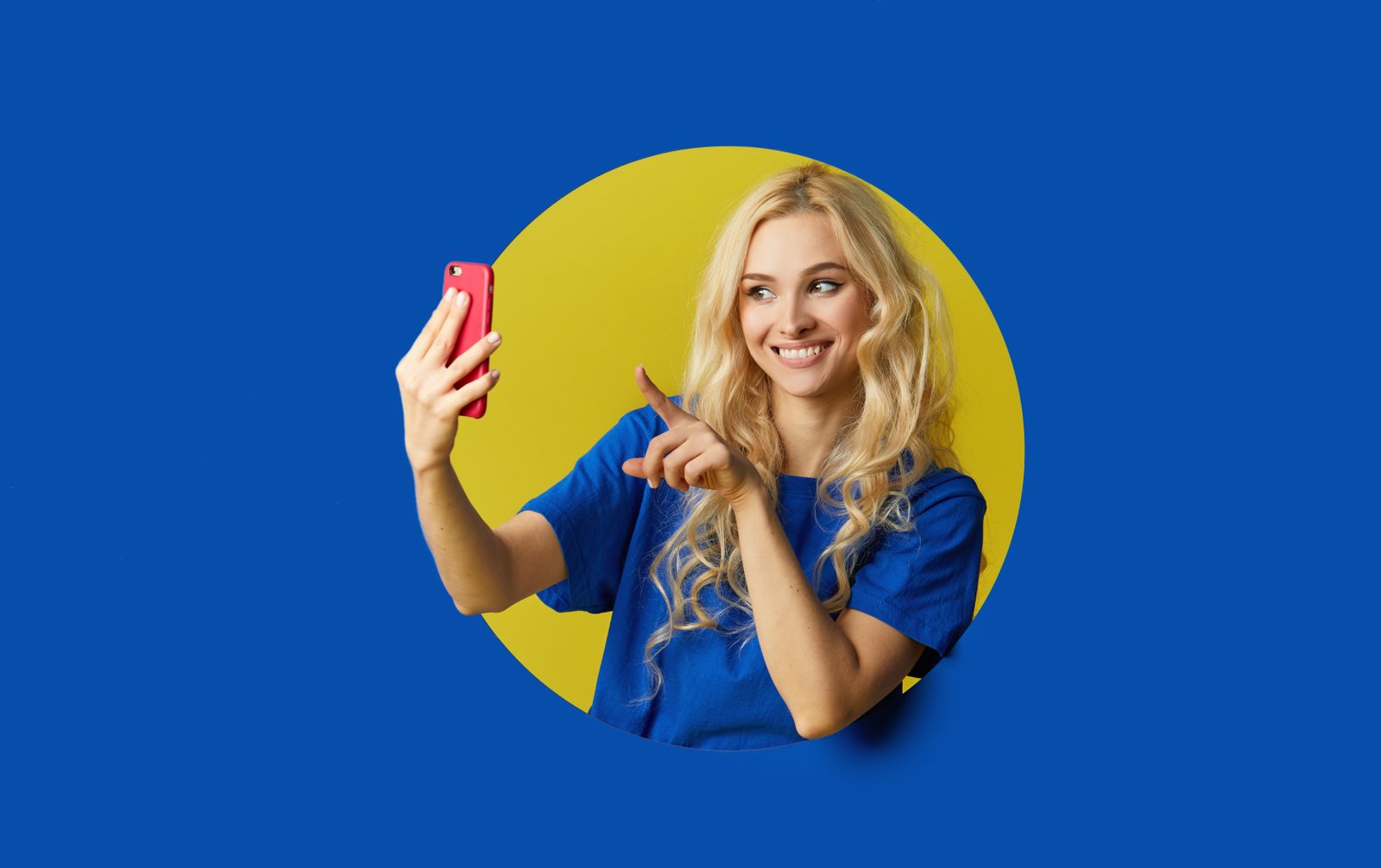 image young happy woman standing blue wall woman peep out hole wall looking side take selfie mobile phone